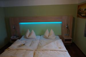 um quarto com uma cama com lençóis brancos e almofadas em Hotel garni Kleindienst em Ursensollen