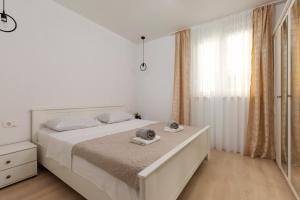 a white bedroom with a bed with towels on it at Apartment Antoni 2 in Podstrana +51 photos