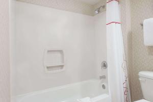 a bathroom with a white tub and a toilet at Value Suites Extended Stay - St Louis in Maryland Heights +1 photo