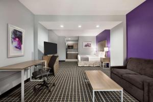 a hotel room with a bed and a desk and a couch at Days Inn by Wyndham Odessa in Odessa
