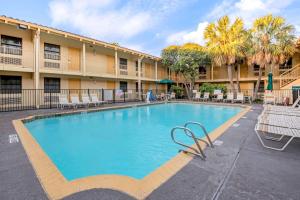 a swimming pool in front of a building with palm trees at La Quinta Inn by Wyndham San Antonio Market Square in San Antonio