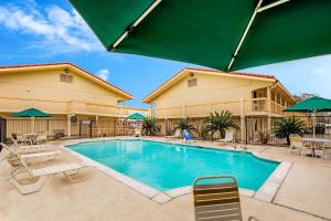 a pool at a hotel with chairs and umbrellas at La Quinta Inn by Wyndham Lufkin in Lufkin