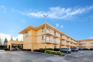 un grand bâtiment jaune avec des voitures garées dans un parking dans l'établissement La Quinta by Wyndham Oakland - Hayward, à Hayward