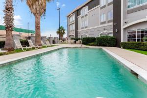 a swimming pool in front of a building with palm trees at La Quinta by Wyndham Seguin in Seguin