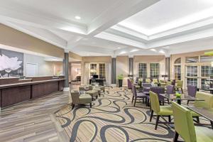 a hotel lobby with tables and chairs and a piano at La Quinta by Wyndham Birmingham Homewood in Birmingham