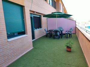 een patio met een tafel en stoelen en een parasol bij Acogedor Apartamento in La Lastrilla