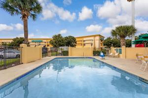 a swimming pool with palm trees and a building at La Quinta by Wyndham Orlando South in Orlando