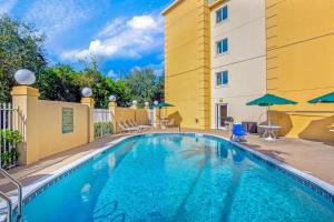 - une piscine avec des chaises et des parasols à côté d'un bâtiment dans l'établissement La Quinta by Wyndham Miami Cutler Bay, à Cutler Ridge