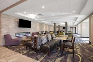 a waiting room with tables and chairs and a tv at La Quinta by Wyndham Rancho Cordova Sacramento in Rancho Cordova