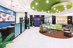 a lobby with a waiting room with green chairs and tables at La Quinta by Wyndham Marshall in Marshall