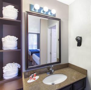 a bathroom with a sink, mirror, and a towel rack at Grand Hotel Orlando at Universal Blvd in Orlando
