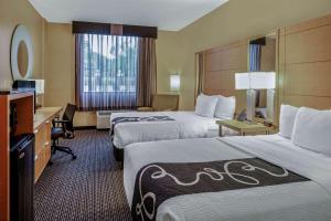 a hotel room with two beds and a desk at La Quinta by Wyndham Naples Downtown in Naples