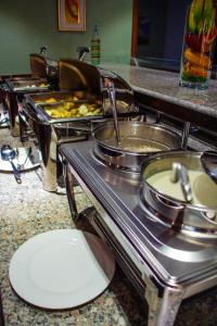 una línea de buffet con muchas ollas y sartenes de comida en Dostar Hotel, en Aktau