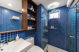 a blue tiled bathroom with a toilet and a sink at Hotel Amber Sukhumvit 85 in Bangkok