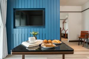 a table with bread and a cup and a tv on a blue wall at Hotel Amber Sukhumvit 85 in Bangkok