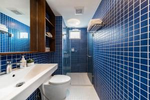 a blue tiled bathroom with a toilet and a sink at Hotel Amber Sukhumvit 85 in Bangkok