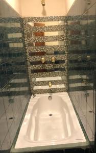 a white tub in a bathroom with a wall of wine bottles at Mini departamento cómodo in Cuenca