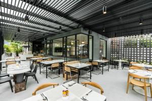 a restaurant with white tables and chairs and windows at Hotel Amber Sukhumvit 85 in Bangkok