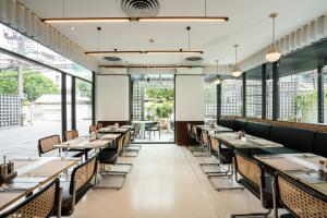 a dining room with tables and chairs and windows at Hotel Amber Sukhumvit 85 in Bangkok