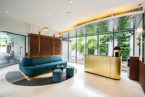 a living room with a blue couch and large windows at Hotel Amber Sukhumvit 85 in Bangkok