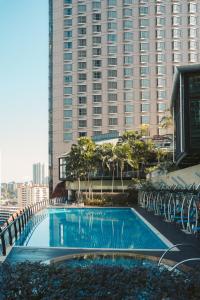 a large swimming pool in front of a tall building at The Gardens – A St Giles Signature Hotel & Residences, Kuala Lumpur in Kuala Lumpur