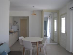 cocina y comedor con mesa blanca y sillas en Meraki Skopelos, en Panormos Skopelos