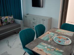 comedor con mesa, sillas y TV en Mamaia Summerland Apartments, en Mamaia