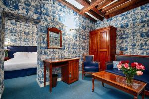 1 dormitorio con papel pintado azul y blanco, cama y escritorio en Relais Hôtel du Vieux Paris en París