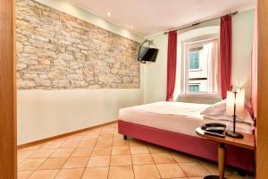 sypialnia z łóżkiem i kamienną ścianą w obiekcie Residence San Giusto w Trieście
