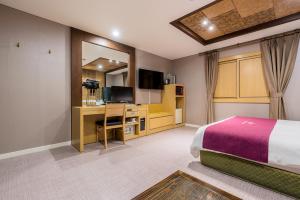 sypialnia z łóżkiem, biurkiem i telewizorem w obiekcie Symphony Hotel w mieście Suwon