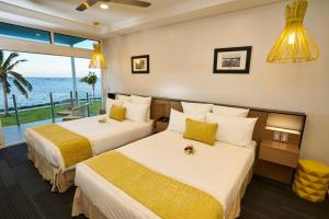 two beds in a hotel room with a view of the ocean at Taumeasina Island Resort in Apia
