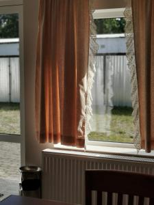 Cette chambre dispose d'une fenêtre avec des rideaux orange. dans l'établissement Pensjonat Dwa Dęby, à Hajnówka