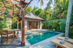 a pool in a backyard with a table and a house at Arkamara Dijiwa Ubud in Ubud