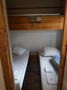 two bunk beds in a room with white sheets at Chalet calme in Saint-Léger-les-Mélèzes