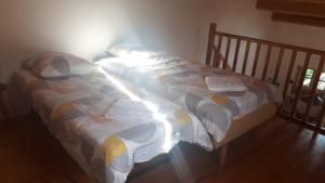 a bed with a comforter on it in a room at Jolie petite maison dans hameau en pleine nature in Taussac-la-Billière