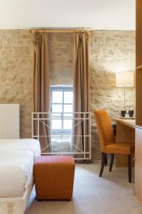 a bedroom with a bed and a desk and a window at Hôtel Le Château Fort de Sedan in Sedan