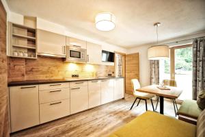 une cuisine avec des placards blancs, une table et une salle à manger dans l'établissement Apart Cäcilia, à Ried im Oberinntal