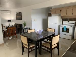 uma cozinha com uma mesa com cadeiras e um frigorífico branco em Private Chalan Pago Apartment em Hagatna