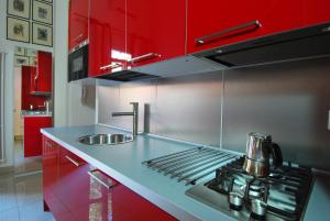 eine rote Küche mit einer Spüle und einem Herd in der Unterkunft GetTheKey Boldrini Lofts in Bologna