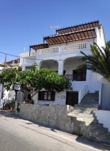 a white house with stairs and a palm tree at Villa Dora Studios in Batsi