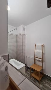 a bathroom with a chair and a bath tub at Maris Apartment in Târgu-Mureş