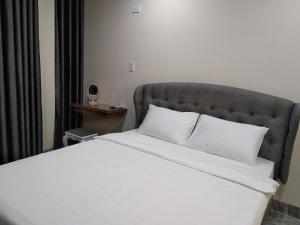 ein Schlafzimmer mit einem weißen Bett mit einem grauen Kopfteil in der Unterkunft PEACE HOTEL in Vũng Tàu