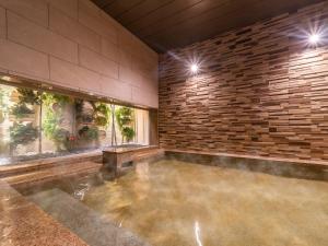 uma grande piscina interior com uma parede de pedra em Super Hotel Beppu Ekimae em Beppu