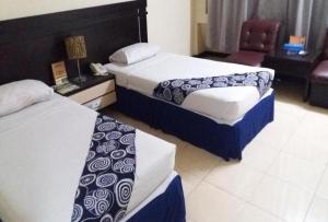 een hotelkamer met 2 bedden en een stoel bij Hotel Bandung Permai Jember in Jember