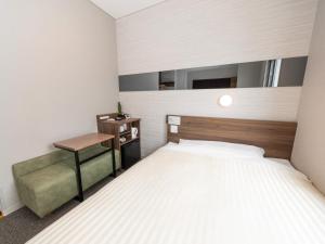 a small bedroom with a bed and a desk at Super Hotel Beppu Ekimae in Beppu