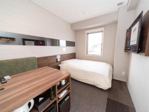 a small bedroom with a bed and a tv at Super Hotel Beppu Ekimae in Beppu