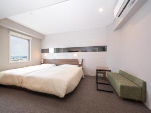 a bedroom with a bed and a couch and a window at Super Hotel Beppu Ekimae in Beppu +84 photos