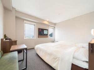 a bedroom with a large white bed and a window at Super Hotel Beppu Ekimae in Beppu