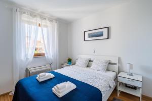 a white bedroom with a blue bed and a window at Downtown Apartments Dorian and Nadia in Opatija