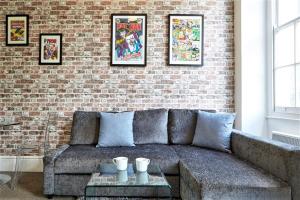 - un salon avec un canapé et un mur en briques dans l'établissement Berkeley Square Pads, à Bristol